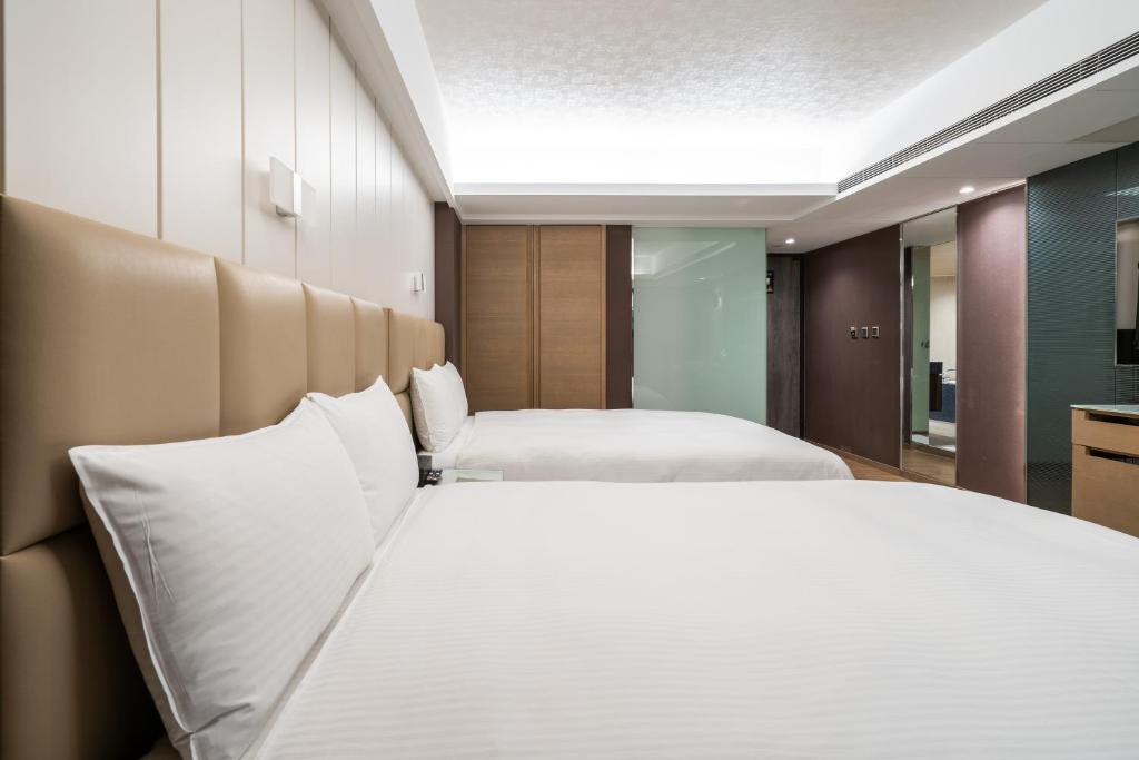 a bedroom with two beds with white pillows at The Cloud Hotel in Kaohsiung