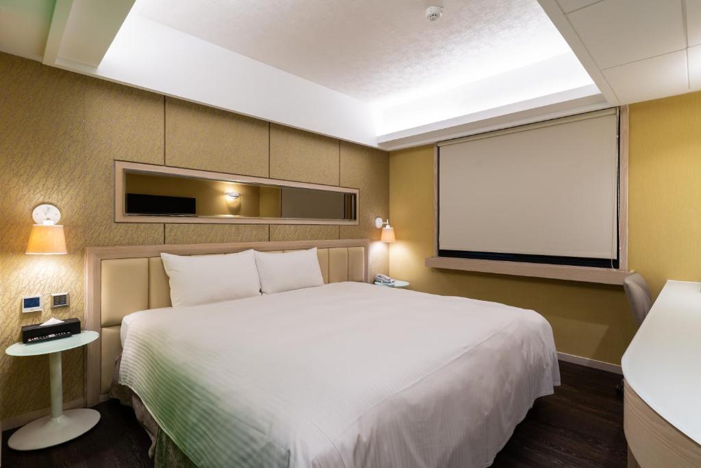 a bedroom with a large white bed and a window at The Cloud Hotel in Kaohsiung