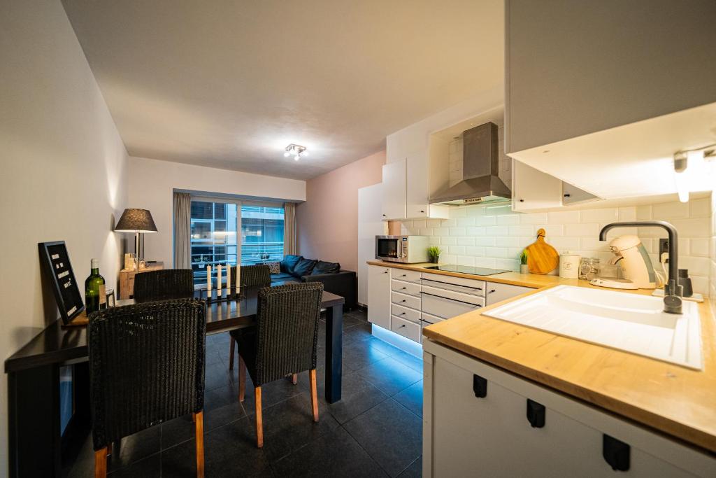 a kitchen with a sink and a table with chairs at Appartement Miete - dichtbij strand en winkels in Bredene