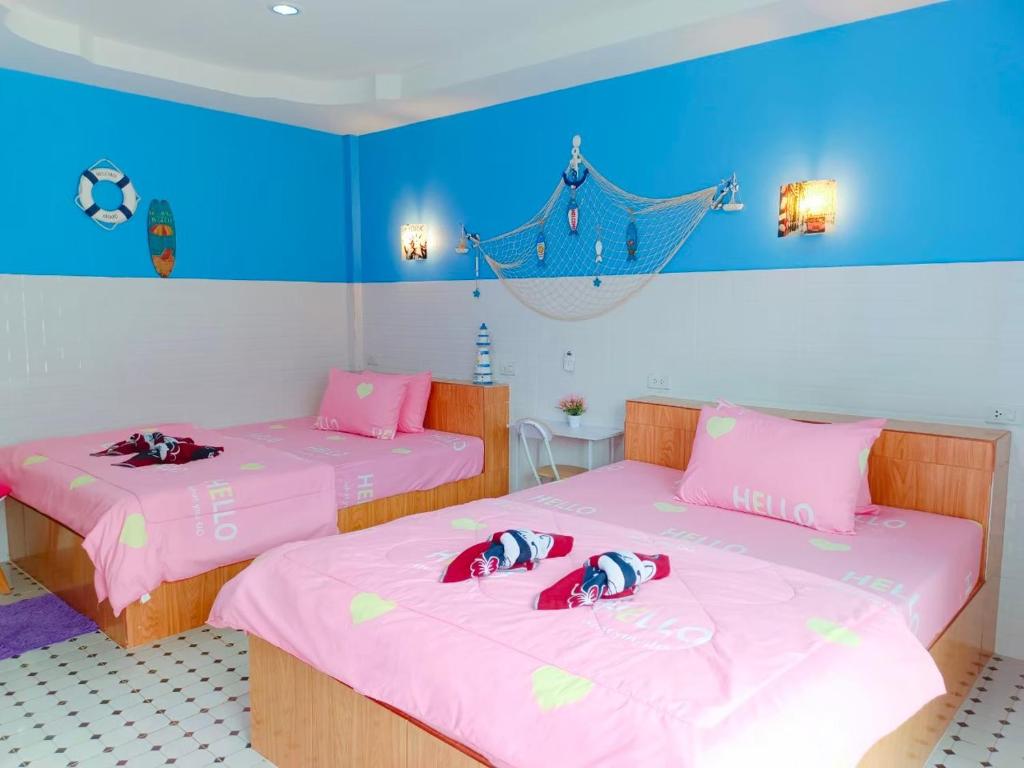 2 camas en una habitación con paredes rosas y azules en Sichon Lalla Beach สิชล ลัลลา บีช, en Sichon