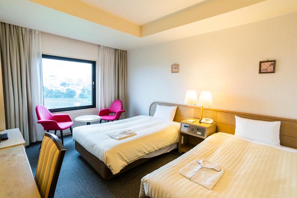 una camera con due letti e sedie rosa di Hotel Sanderson a Maebashi