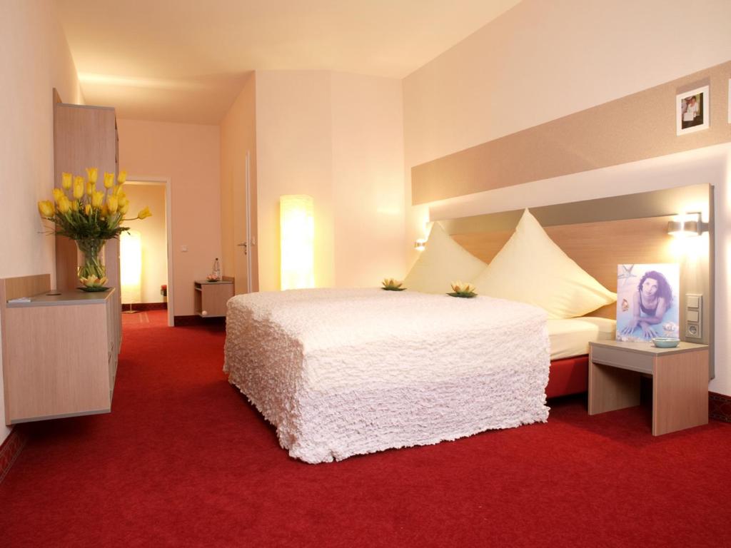 a bedroom with a large white bed and a red carpet at Gästehaus Catherine in Zierenberg