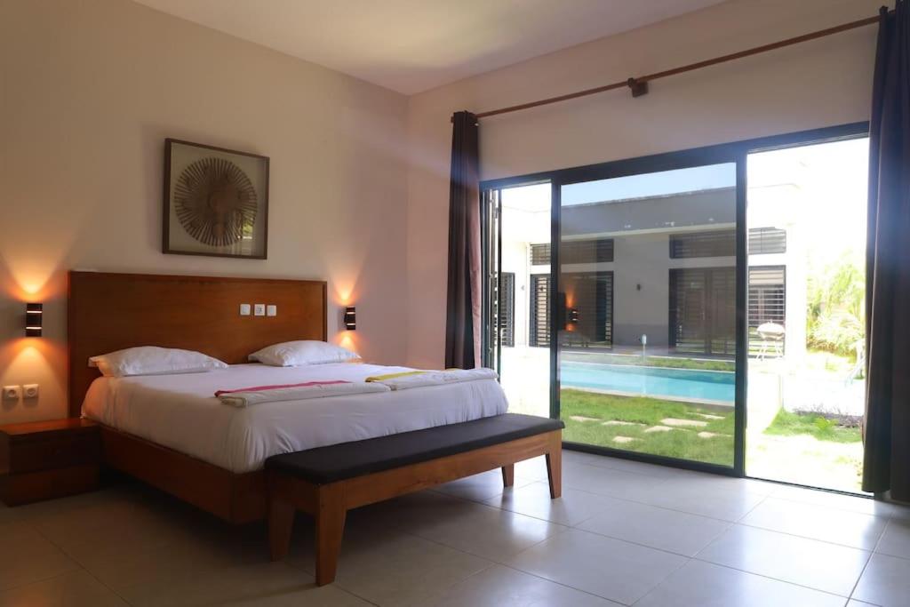 a bedroom with a bed and a large sliding glass door at Villa Tiana - 3Bedroom Villa with private pool. in Kribi
