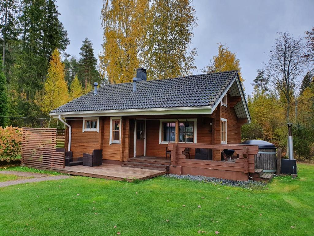 een klein houten huis met een groot houten terras bij Peaceful log cabin in the country in Nurmijärvi