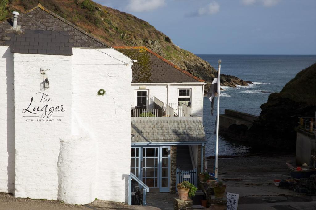 a white building with the oyster restaurant next to the ocean at Lugger Hotel ‘A Bespoke Hotel’ in Portloe