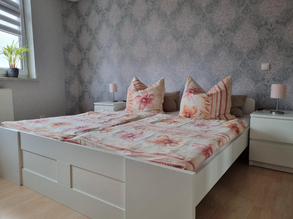 1 dormitorio con 1 cama blanca grande con sábanas y almohadas rosas en Ferienwohnung Am Anger, en Diedorf