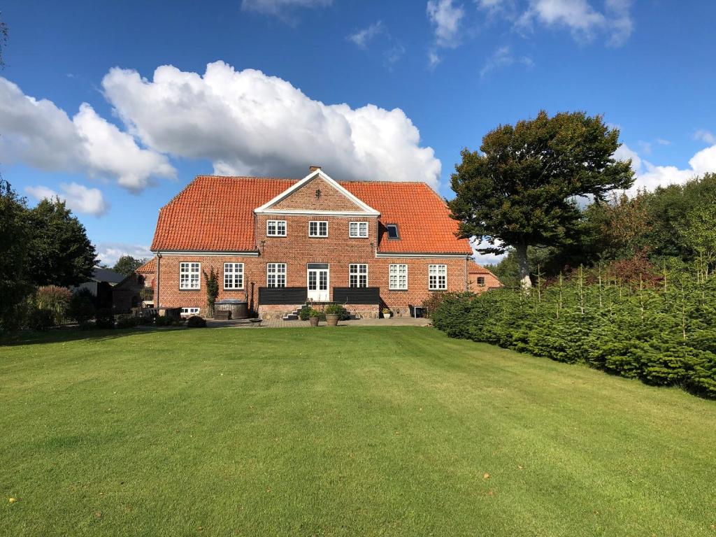 a large brick house with red roofs on a green field at Store Sand in Vemb
