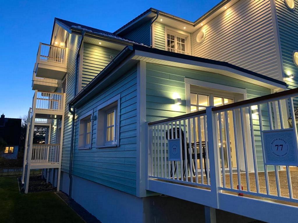 ein blaues Haus mit einem Geländer auf einer Veranda in der Unterkunft Seventy Seven Beach Hotel in Timmendorfer Strand