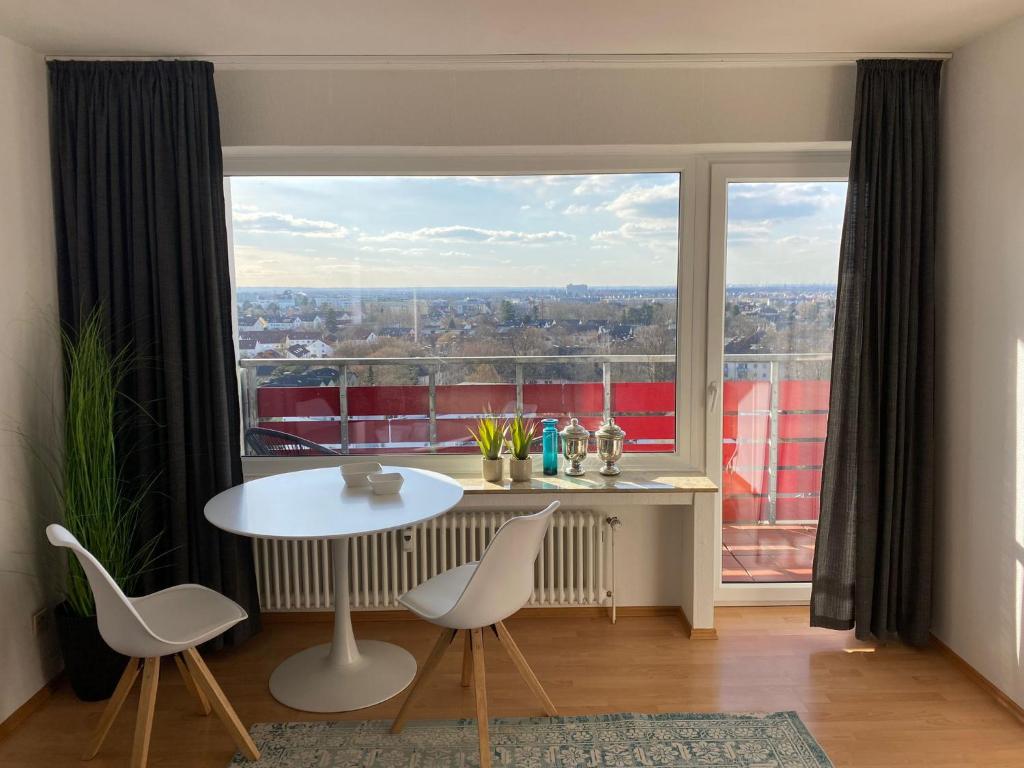 Cette chambre dispose d'une grande fenêtre et d'une table avec des chaises. dans l'établissement Weitblick 2, à Sankt Augustin