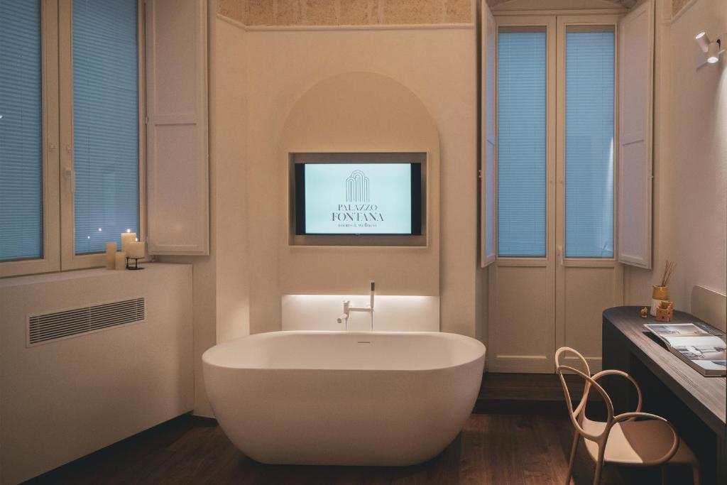 普利亞區格拉維納的住宿－Palazzo Fontana B&B e SPA，带浴缸的浴室和墙上的电视