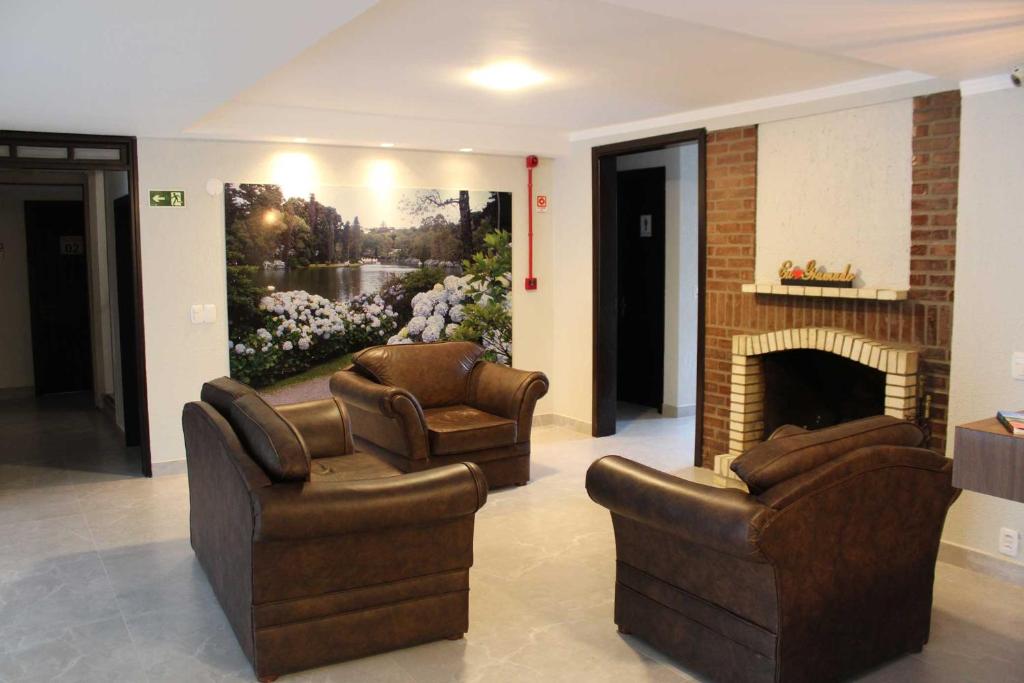 a living room with two chairs and a fireplace at Hotel San Lucas in Gramado