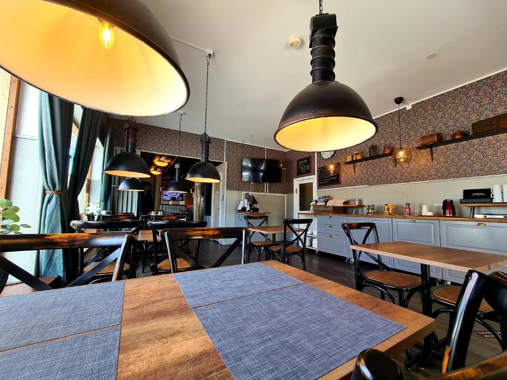 a restaurant with wooden tables and chairs and pendant lights at Dala-Järna Hotell och Vandrarhem in Dala-Järna