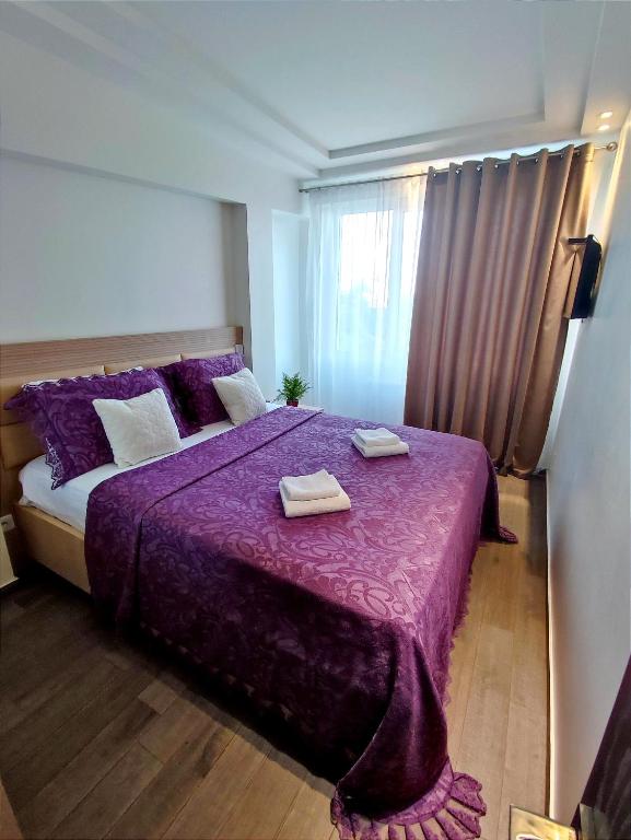 a bedroom with a purple bed with two towels on it at 2BR+living downtown Chișinău in Chişinău