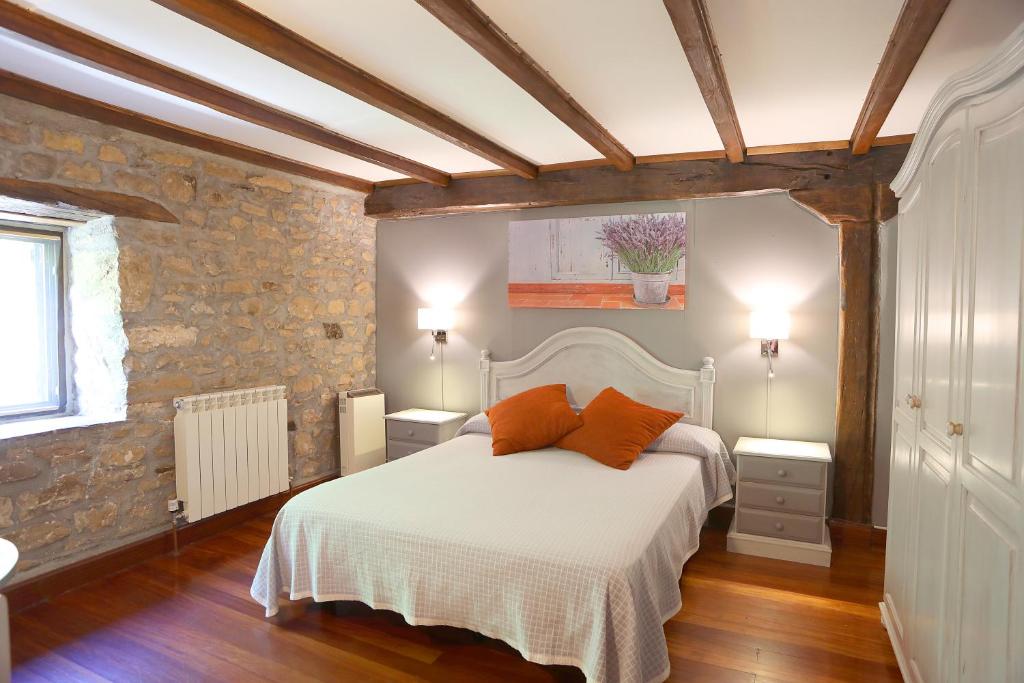 1 dormitorio con 1 cama blanca y 2 almohadas de color naranja en Casa Rural Haitzetxea, en Zugarramurdi