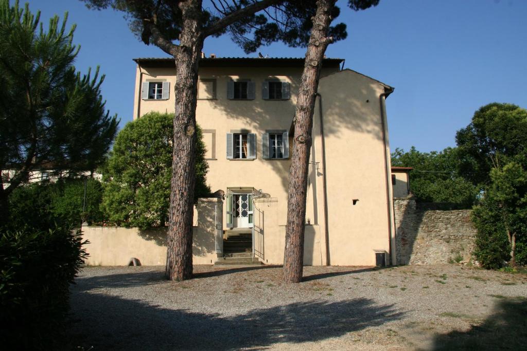 une grande maison blanche avec des arbres devant elle dans l'établissement Villa Guadagni Cappelli, à Arezzo