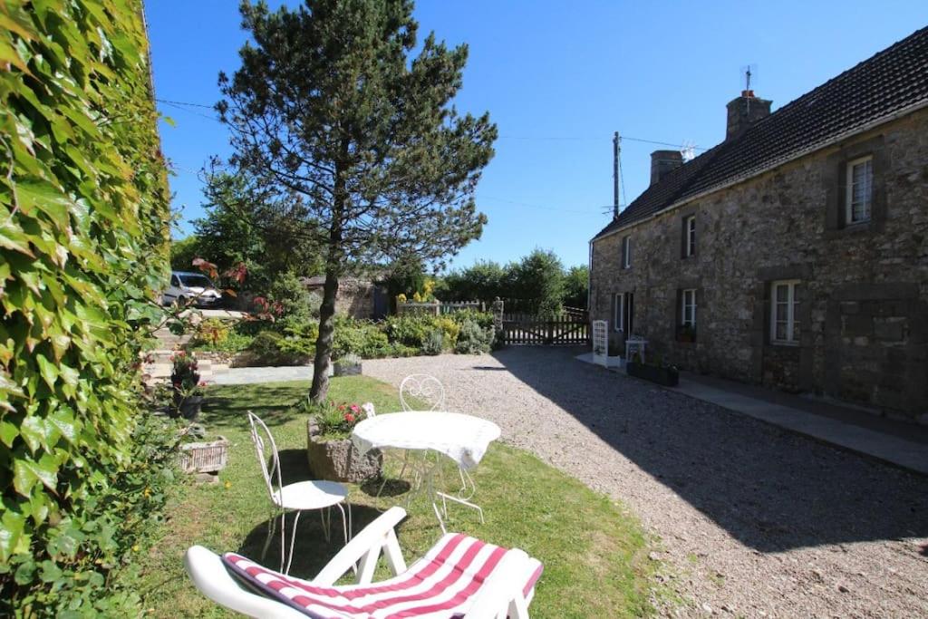 einen Tisch und Stühle in einem Hof neben einem Gebäude in der Unterkunft Petite maison entre mer et campagne in Les Pieux