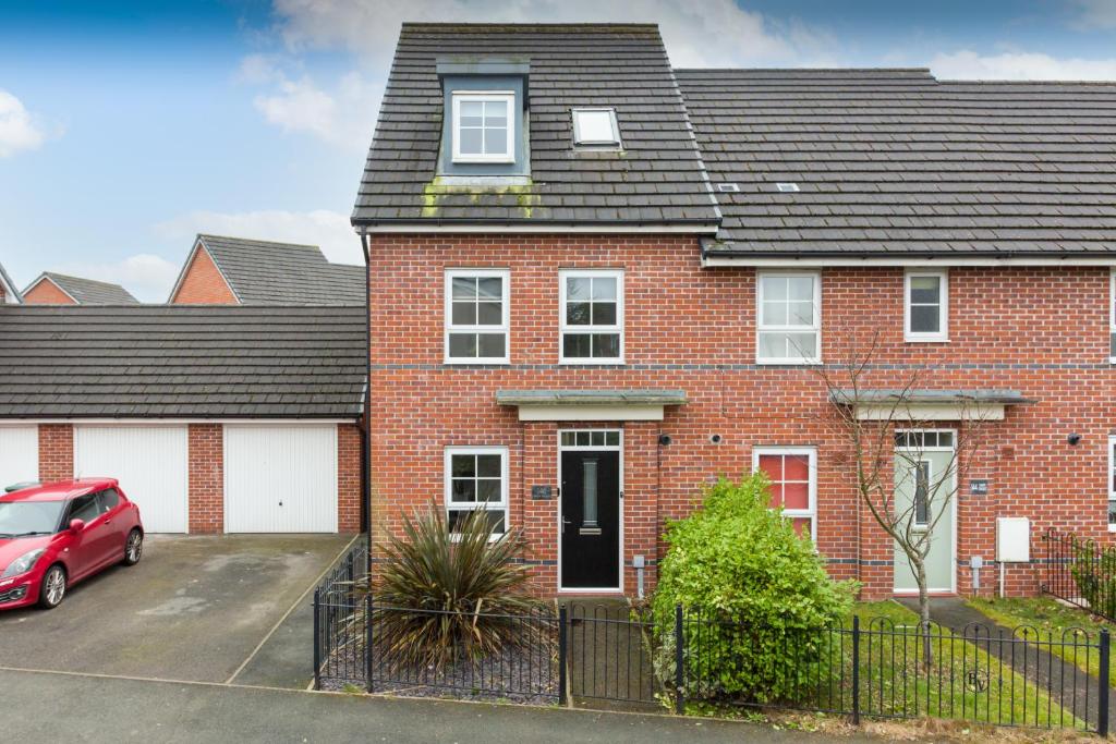 a red brick house with a car parked in the driveway at Main Street Town House in Leyland