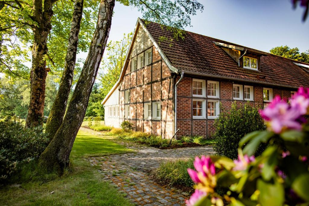 stary ceglany dom z różowymi kwiatami przed nim w obiekcie Thuers im Busch - Gute Stube w Münster