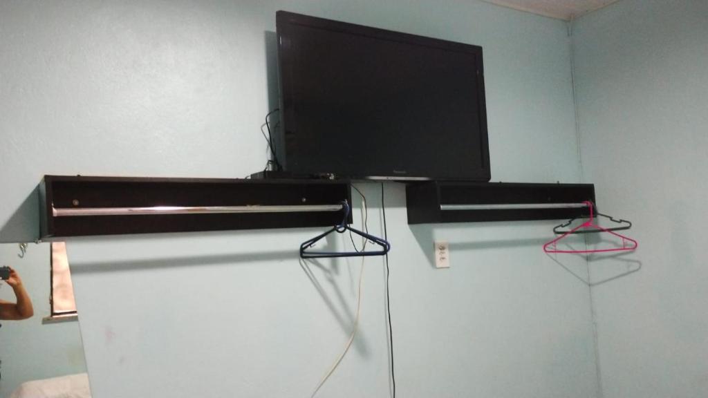 a black stand with a flat screen tv on a wall at Alvorada Suite in Manaus