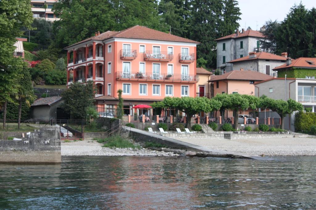 a pink building next to a body of water at Albergo Riva in Reno Di Leggiuno