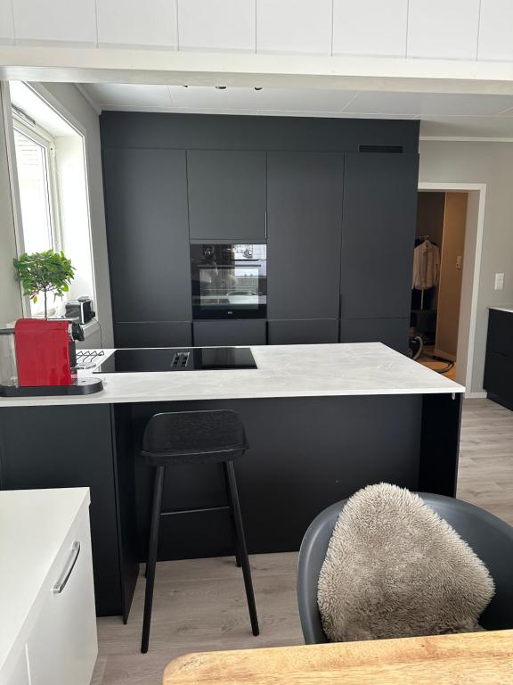 eine Küche mit einer schwarz-weißen Theke und einem Stuhl in der Unterkunft Lofoten Kabelvåg-small apartment in Kabelvåg