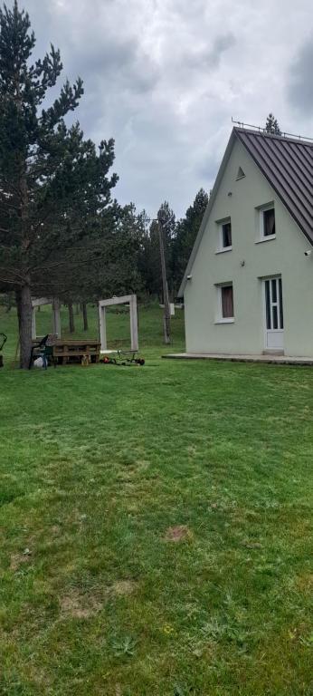 a white house in a field with a picnic table at Vikendica Mateo in Blidinje