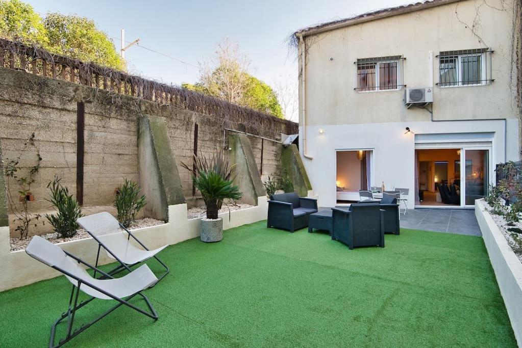 un patio con césped y sillas verdes y un edificio en Le 002 - T3 climatisé avec terrasse, en Marsella