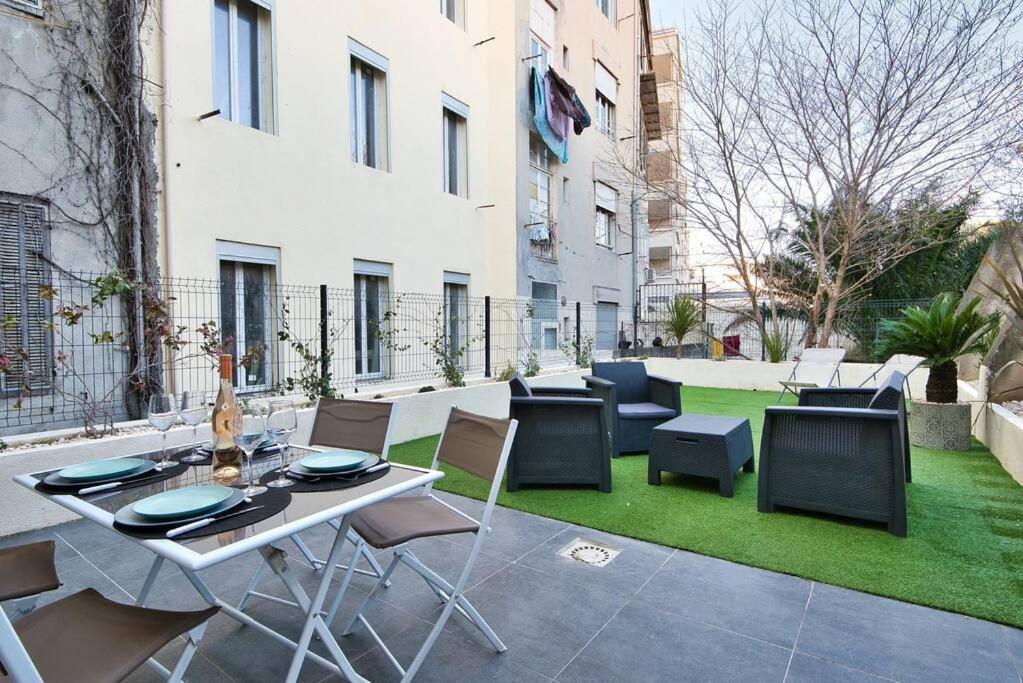 a patio with a table and chairs and grass at Le 002 - T3 climatisé avec terrasse in Marseille