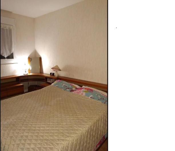 een slaapkamer met een bed en een tafel met een lamp bij Chambre 5 minutes de la gare à pieds in Les Mureaux