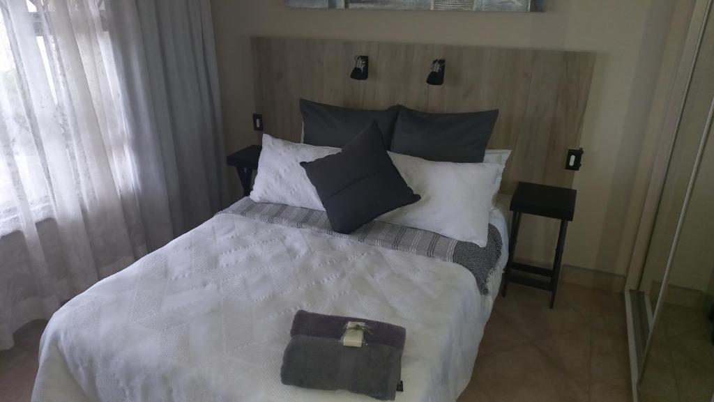 sypialnia z dużym łóżkiem z czarno-białymi poduszkami w obiekcie 8 On Eagle Self Catering Apartment w mieście Umtentweni
