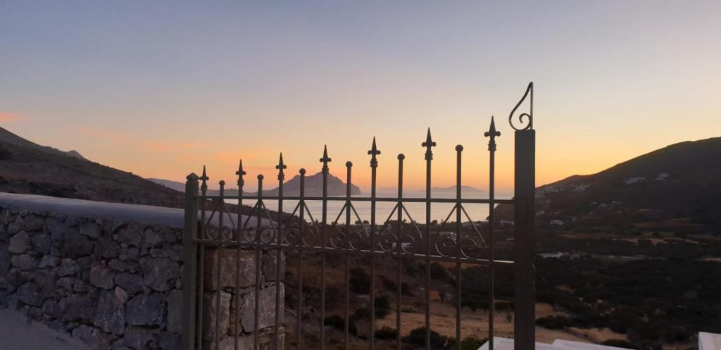 una valla de hierro forjado con la puesta de sol en el fondo en Amorgos Villa Handras / Main villa, en Amorgós