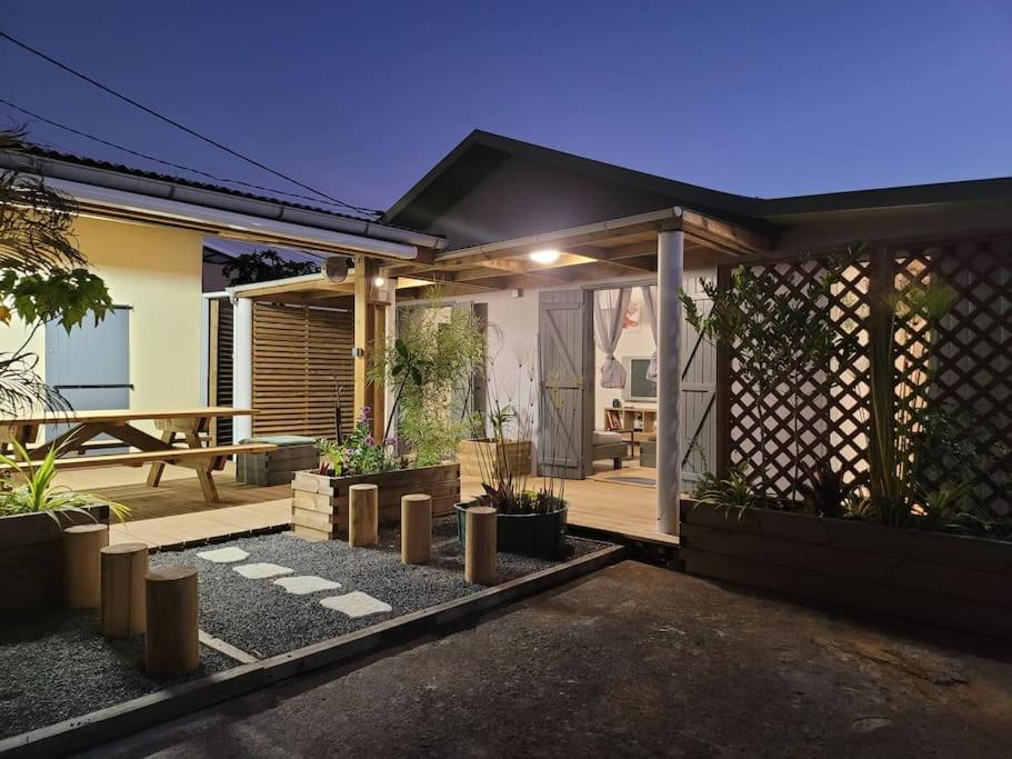 a house with a patio with a table and a fence at Maison de vacances, découvrir le sud de la Réunion in Petite Île