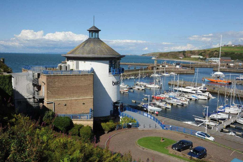 a building with a tower next to a marina with boats at HAVEN STUDIO GROUND FLOOR in Whitehaven