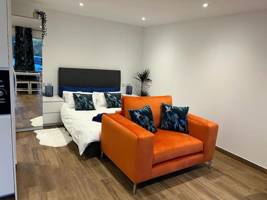 um quarto com uma cadeira laranja e uma cama em Cosy Detached Annexe With Free Off Street Parking em Milton Keynes
