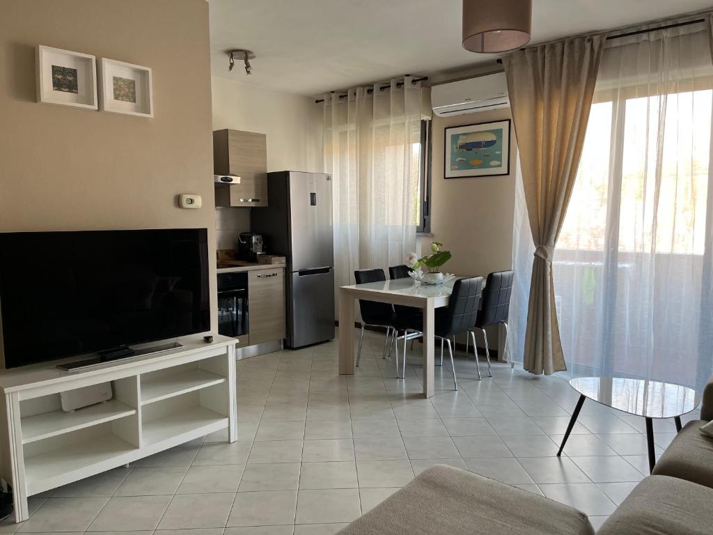 ein Wohnzimmer mit einem TV und einem Tisch mit Stühlen in der Unterkunft Lovely Apartment in Parma
