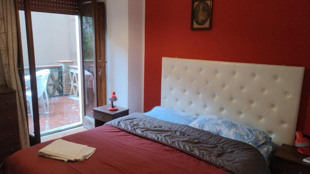 a bedroom with a bed with a red wall at IL PORTICCIOLO Apartment - Via Umberto 25 in Giardini Naxos