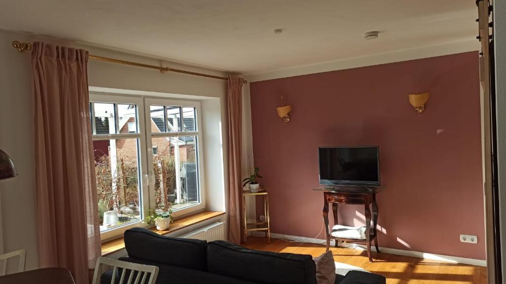 a living room with a couch and a tv and a window at FeWo mit Heimatgefühl in Ratekau