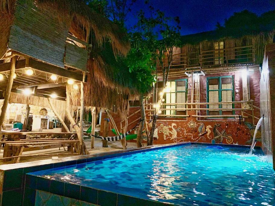 una piscina frente a una casa por la noche en Capiz Beach Villa w/ pool (entire cottage for 12) en Calatagan