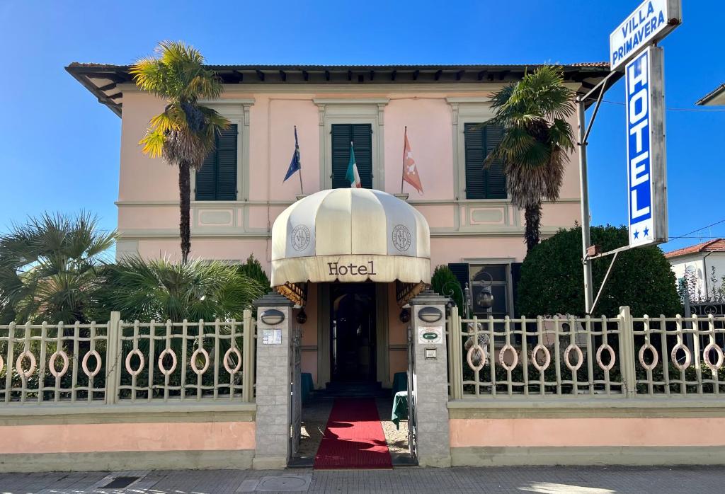 a building with a gate and a building with palm trees at Hotel Villa Primavera in Pisa