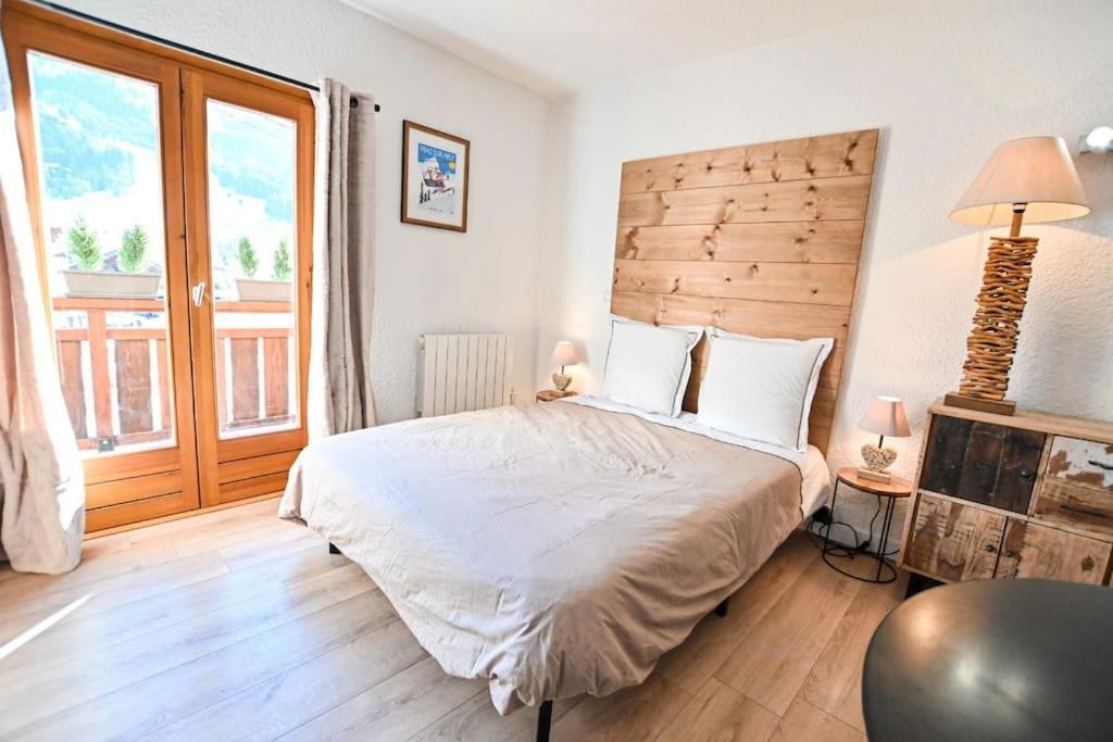 1 dormitorio con 1 cama grande y cabecero de madera en Le balcon des neiges, en Praz-sur-Arly