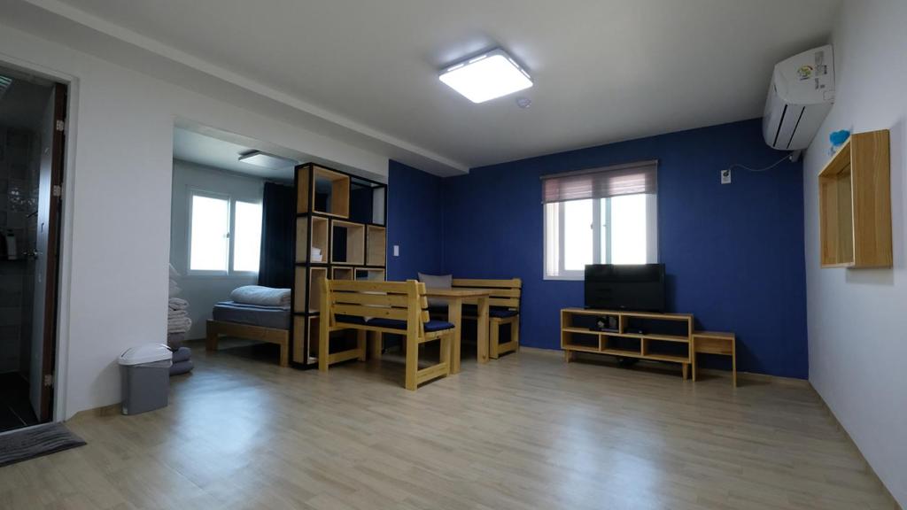 sala de estar con paredes azules, mesa y sillas en Ein House, en Gongju