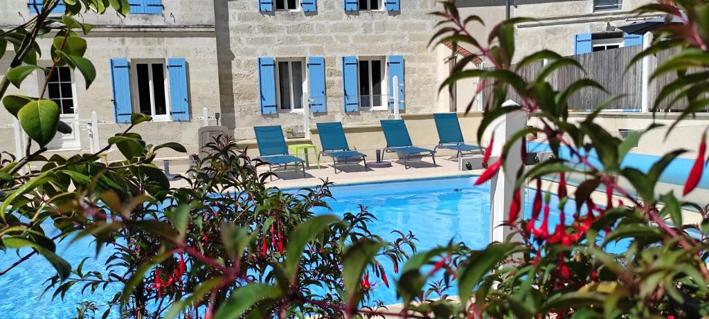 - une piscine avec des chaises bleues en face d'un bâtiment dans l'établissement Appart'é Nature L'ESCALE - Saintes - Piscine, Parking, Terrasse, Wifi, à Chaniers