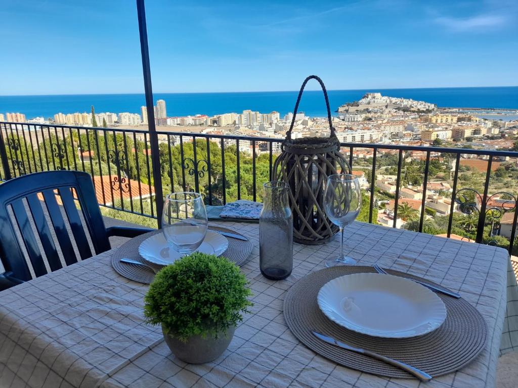 a table with plates and wine glasses on a balcony at Apartamentos Serenity in Peniscola