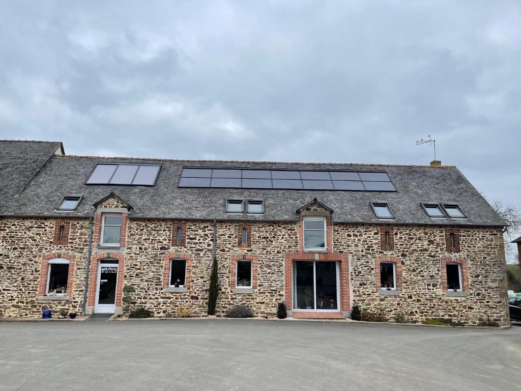 un gran edificio de piedra con paneles solares en el techo en Biologite, en Argentré-du-Plessis