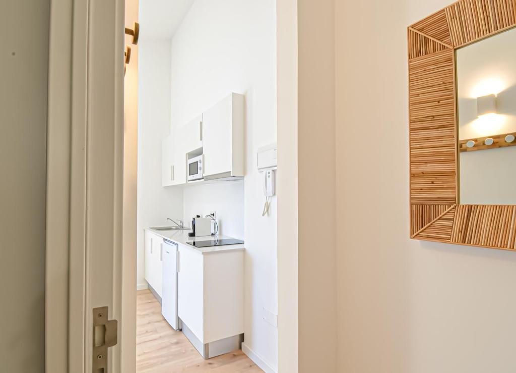 eine Küche mit weißen Schränken, einem Waschbecken und einem Spiegel in der Unterkunft LAA Studios in Coimbra