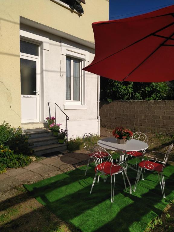 een tafel en stoelen met een rode parasol bij Warm and Cosy in Nevers