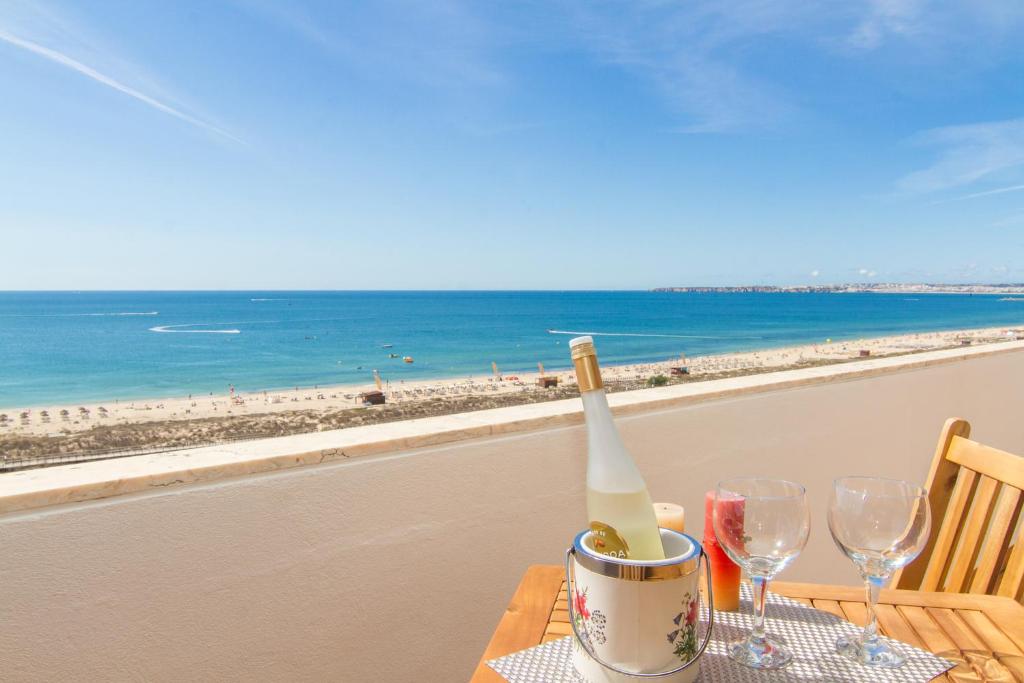 una mesa con una botella de vino y copas en la playa en Alvor Sun, en Alvor