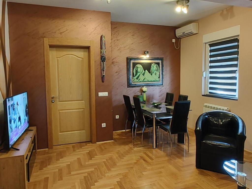 ein Esszimmer mit einem Tisch, Stühlen und einem TV in der Unterkunft Apartment StefanA in Belgrad