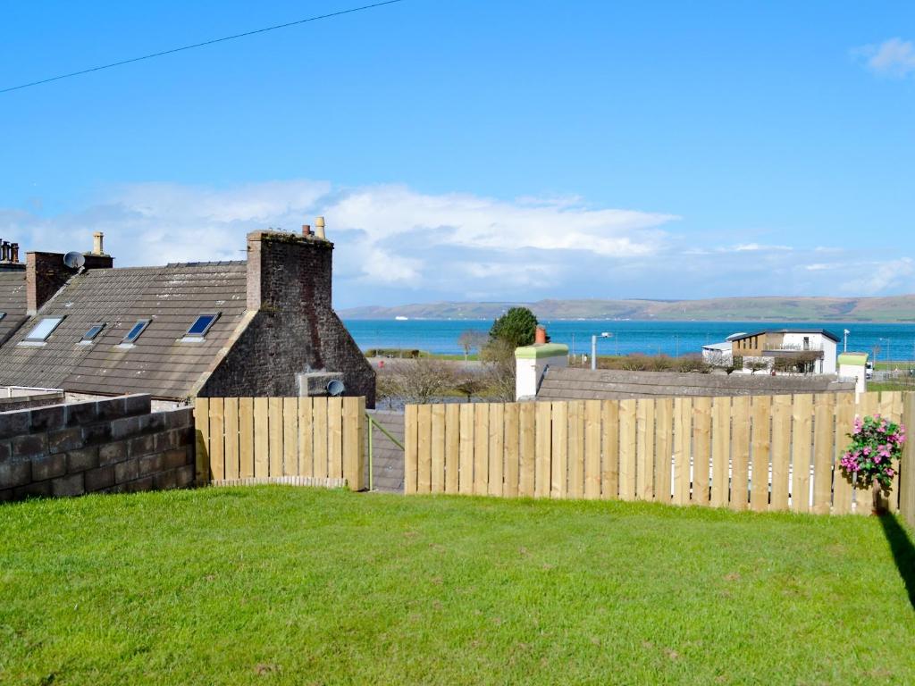 a fence in front of a house with the ocean in the background at Park View Cottage in Stranraer