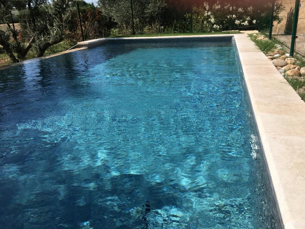 a swimming pool with blue water in a yard at CHEZ NOUS in Mérindol